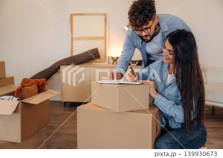 Focused, writing on the paper. Couple reviewing documents and planning their new home after moving Focused, writing on the paper. Couple reviewing documents and planning their new home after moving 139930673
