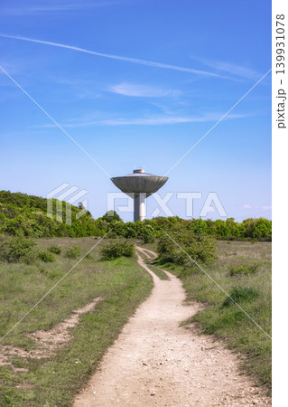 Water tower standing tall in a green meadow with a natural path Water tower standing tall in a green meadow with a natural path 139931078