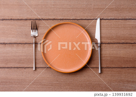 An empty ceramic round plate, kitchen utensils for a dinner table. An empty plate 139931692