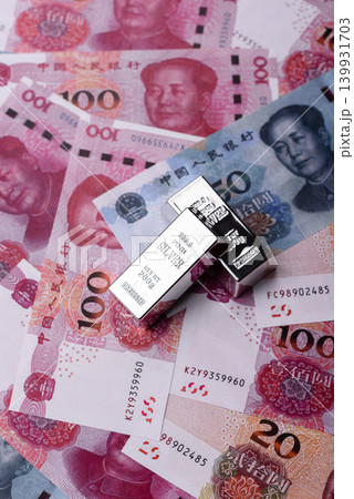 A silver bar, white metal against a backdrop of Chinese money, as a concept for the sales market A silver bar, white metal against a backdrop of Chinese money, as a concept for the sales market 139931703