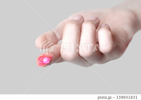 Popular pink capsule face cream on finger, close up grey background Popular pink capsule face cream on finger, close up grey background 139931831
