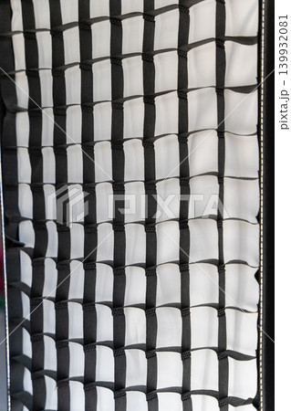 Black and white softbox lighting equipment with a grid pattern, positioned on a stand, showcasing a textured surface Black and white softbox lighting equipment with a grid pattern, positioned on a stand, showcasing a textured surface 139932081