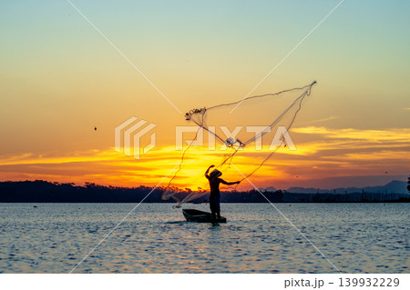 Traditional Fisherman Working on Wooden Boat at Sunset 139932229