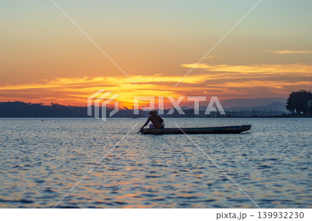 Traditional Fisherman Working on Wooden Boat at Sunset 139932230