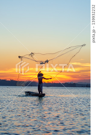 Traditional Fisherman Working on Wooden Boat at Sunset 139932232