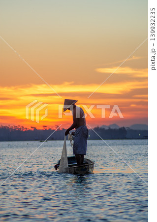 Traditional Fisherman Working on Wooden Boat at Sunset 139932235