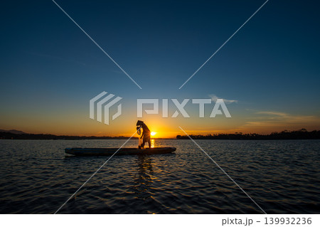 Traditional Fisherman Working on Wooden Boat at Sunset 139932236