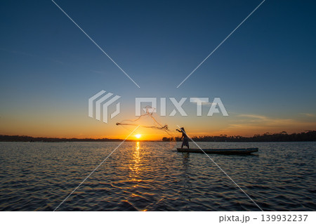 Traditional Fisherman Working on Wooden Boat at Sunset 139932237