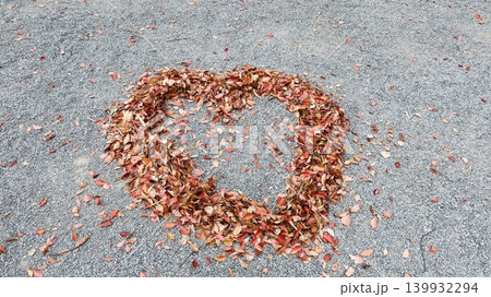close up of a heart shape made of autumn leaves in red, orange and brown on the gravel ground close up of a heart shape made of autumn leaves in red, orange and brown on the gravel ground 139932294