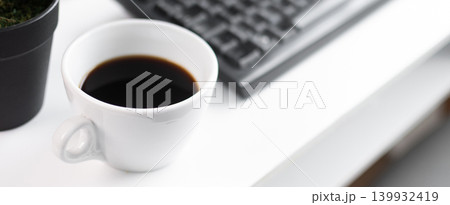 Black Coffee Cup on Minimal White Desk with Keyboard and Plant 139932419