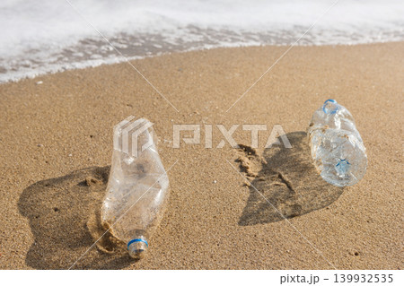 Dirty plastic bottles washed ashore on the sandy beach. Marine pollution, save the oceans and ecology concept. 139932535