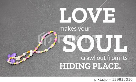 A dark, flat background with a colorful beaded necklace on the left. . A love quote in large white letters is to the right of the necklace. The beads are various shades of purple, pink, and yellow. A dark, flat background with a colorful beaded necklace on the left. . A love quote in large white letters is to the right of the necklace. The beads are various shades of purple, pink, and yellow. 139933010