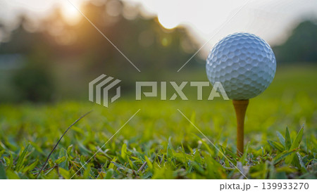 Golf ball on tee in a beautiful golf course with morning sunshine. Golf ball on tee in a beautiful golf course with morning sunshine. 139933270