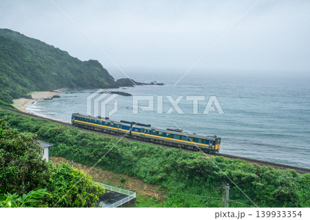 雨の中、日本海沿いを走る山陰本線の特急列車 139933354