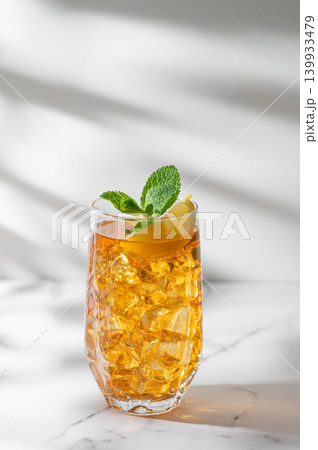 Iced tea with lemon and mint in a glass on a marble background with shadows. 139933479