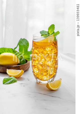 Iced tea with lemon and mint in a glass on a marble countertop with citrus fruits 139933481