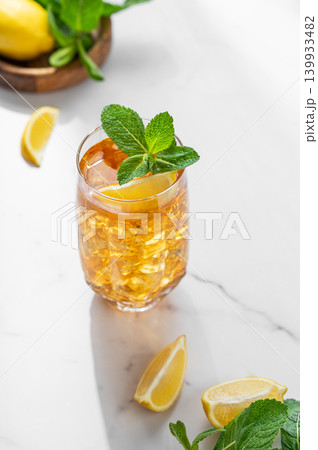 Iced tea with lemon and mint in a glass on a marble countertop with citrus fruits 139933482