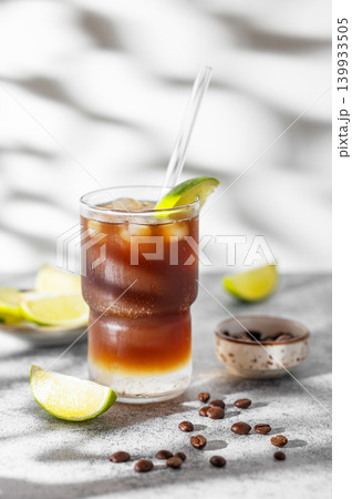 Cold Coffee Tonic Drink With Lime and Ice on light background with shadows Cold Coffee Tonic Drink With Lime and Ice on light background with shadows 139933505