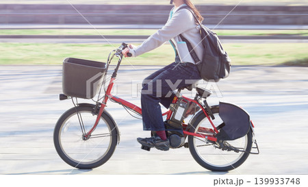 電動自転車に乗って移動するカジュアルな服装の女性 電動自転車に乗って移動するカジュアルな服装の女性 139933748
