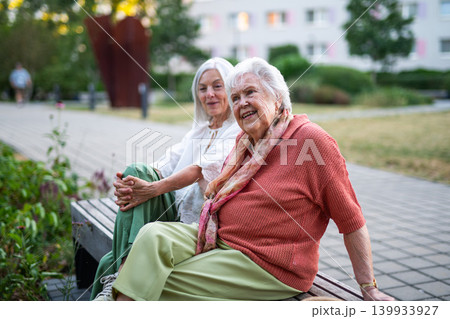 Elderly mother sitting on bench with adult daughter. 139933927