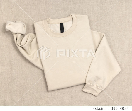 Blank beige unisex sweatshirt mockup, folded crewneck flat lay with copy space on front and sleeve Blank beige unisex sweatshirt mockup, folded crewneck flat lay with copy space on front and sleeve 139934035