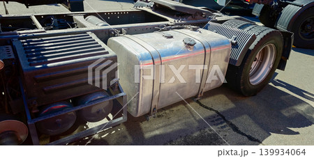 Metal gas tank of a truck positioned beside the chassis, showcasing the vehicle's fuel system and structural components in a clear outdoor setting 139934064