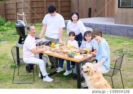 庭でバーベキューを楽しむ家族と犬 庭でバーベキューを楽しむ家族と犬 139934126