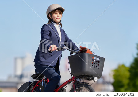 青空の下で電動自転車に乗る笑顔の女性 139934202