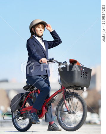 ヘルメットを着用して電動自転車で通勤する若い女性 139934203
