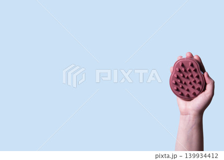 Scalp massage with exfoliating brush on blue background. Illustration of washing routine. Concept of scalp care, trichology, natural cosmetics, and home wellness therapy Scalp massage with exfoliating brush on blue background. Illustration of washing routine. Concept of scalp care, trichology, natural cosmetics, and home wellness therapy 139934412