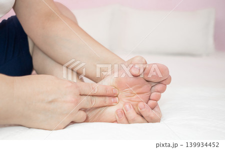 Woman massaging her sole of foot, self massage. Foot pain relief and relaxation. Woman massaging her sole of foot, self massage. Foot pain relief and relaxation. 139934452