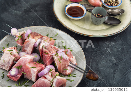 Uncooked pork kebabs with onion on skewers Uncooked pork kebabs with onion on skewers 139935012