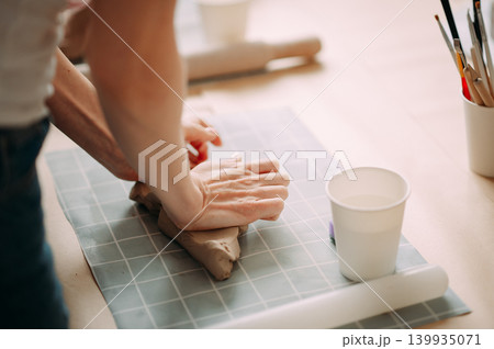 close-up female hands make a clay, align the shape with special tools in the workshop close-up female hands make a clay, align the shape with special tools in the workshop 139935071
