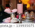 A tiered stand showcases an assortment of pink and white meringues during a gathering. 139935075