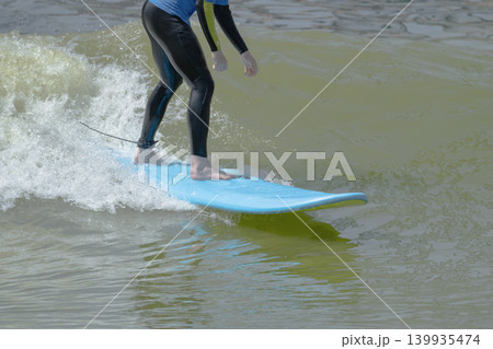 Action shot of a surfer riding an wave on a bodyboard with splashing white water on a sunny day. Action shot of a surfer riding an wave on a bodyboard with splashing white water on a sunny day. 139935474