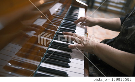 A woman plays the piano, focusing on the hand and the keys. Elderly pianist's hands, close-up. Piano lessons at a music school. The musician composes a new melody A woman plays the piano, focusing on the hand and the keys. Elderly pianist's hands, close-up. Piano lessons at a music school. The musician composes a new melody 139935593