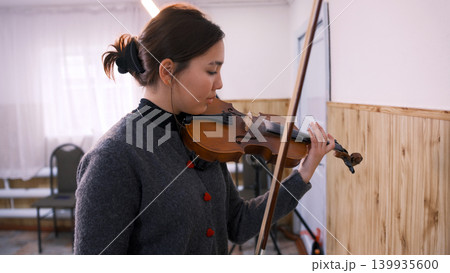 A beautiful young Asian student is learning to play the violin. A young woman plays the violin at a music school. The musician composes a new melody A beautiful young Asian student is learning to play the violin. A young woman plays the violin at a music school. The musician composes a new melody 139935600