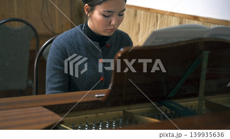 Portrait of a young Asian pianist intently playing the piano. A young female student is learning to play the piano at a music school. The concept of inspiration 139935636