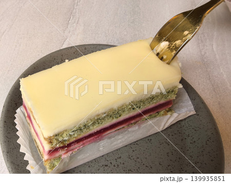 Delicious layered cake served on a sleek gray plate with golden fork Delicious layered cake served on a sleek gray plate with golden fork 139935851