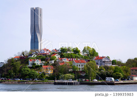 Colony of small wooden historic houses on the Slottsberget mountain with the tallest Scandinavian building Karlatornet skycraper in Lindholmen in background, Gothenburg, Sweden 139935983