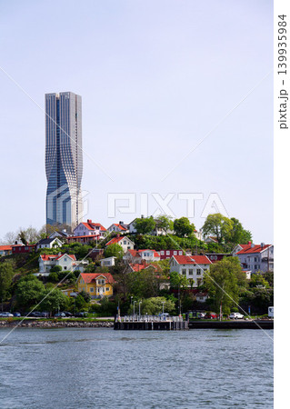 Colony of small wooden historic houses on the Slottsberget mountain with the tallest Scandinavian building Karlatornet skycraper in Lindholmen in background, Gothenburg, Sweden Colony of small wooden historic houses on the Slottsberget mountain with the tallest Scandinavian building Karlatornet skycraper in Lindholmen in background, Gothenburg, Sweden 139935984