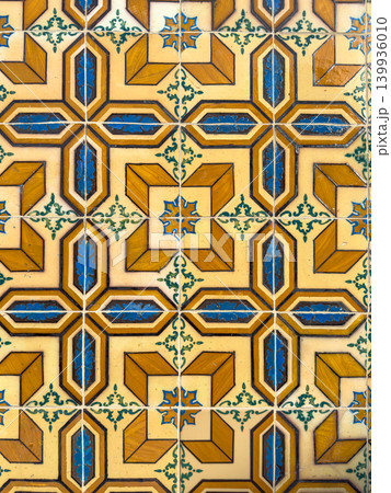 Ornate vintage ceramic wall tiles featuring a complex geometric pattern in ochre yellow cobalt blue and cream hues with intricate floral motifs and a glossy finish capturing Mediterranean charm 139936010