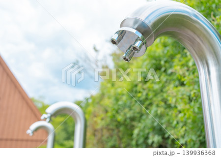 Close up of a modern stainless steel outdoor shower head in a public park resort. Refreshing water source for hygiene and cooling down on hot summer days Close up of a modern stainless steel outdoor shower head in a public park resort. Refreshing water source for hygiene and cooling down on hot summer days 139936368