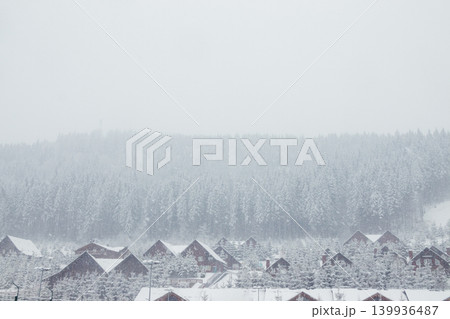 A snowstorm in the mountains sweeps up wooden houses. Wooden houses and Christmas trees in the snow. Carpathians. Ukraine A snowstorm in the mountains sweeps up wooden houses. Wooden houses and Christmas trees in the snow. Carpathians. Ukraine 139936487