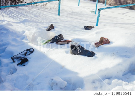 Footprints and old shoes on pure white snow on a cold sunny day, in the blurry background. Footprints and old shoes on pure white snow on a cold sunny day, in the blurry background. 139936541