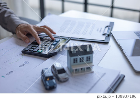 Financial advisor calculating analyzing real estate and car loan budget percentages. Real estate and automotive financial planning concept. Financial advisor calculating analyzing real estate and car loan budget percentages. Real estate and automotive financial planning concept. 139937196