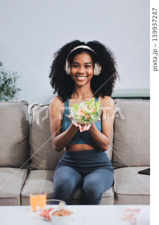 Young nutritionist showing bell peppers during an online video call consulting about healthy eating, sitting at home at a table with vegetables, laptop and measuring tape Young nutritionist showing bell peppers during an online video call consulting about healthy eating, sitting at home at a table with vegetables, laptop and measuring tape 139937287