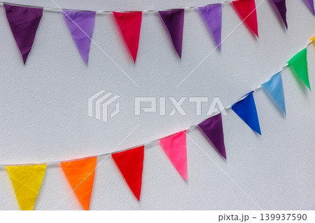 Colorful bunting flags on white wall for party celebration. Background with copy space 139937590