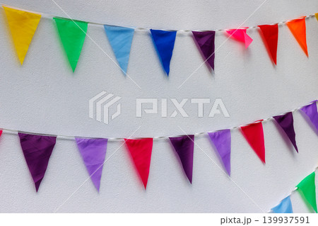Colorful bunting flags on white wall for party celebration. Background with copy space Colorful bunting flags on white wall for party celebration. Background with copy space 139937591