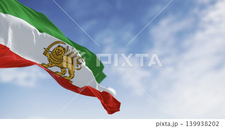 Iran Pahlavi era Lion and Sun flag waving against blue sky 139938202